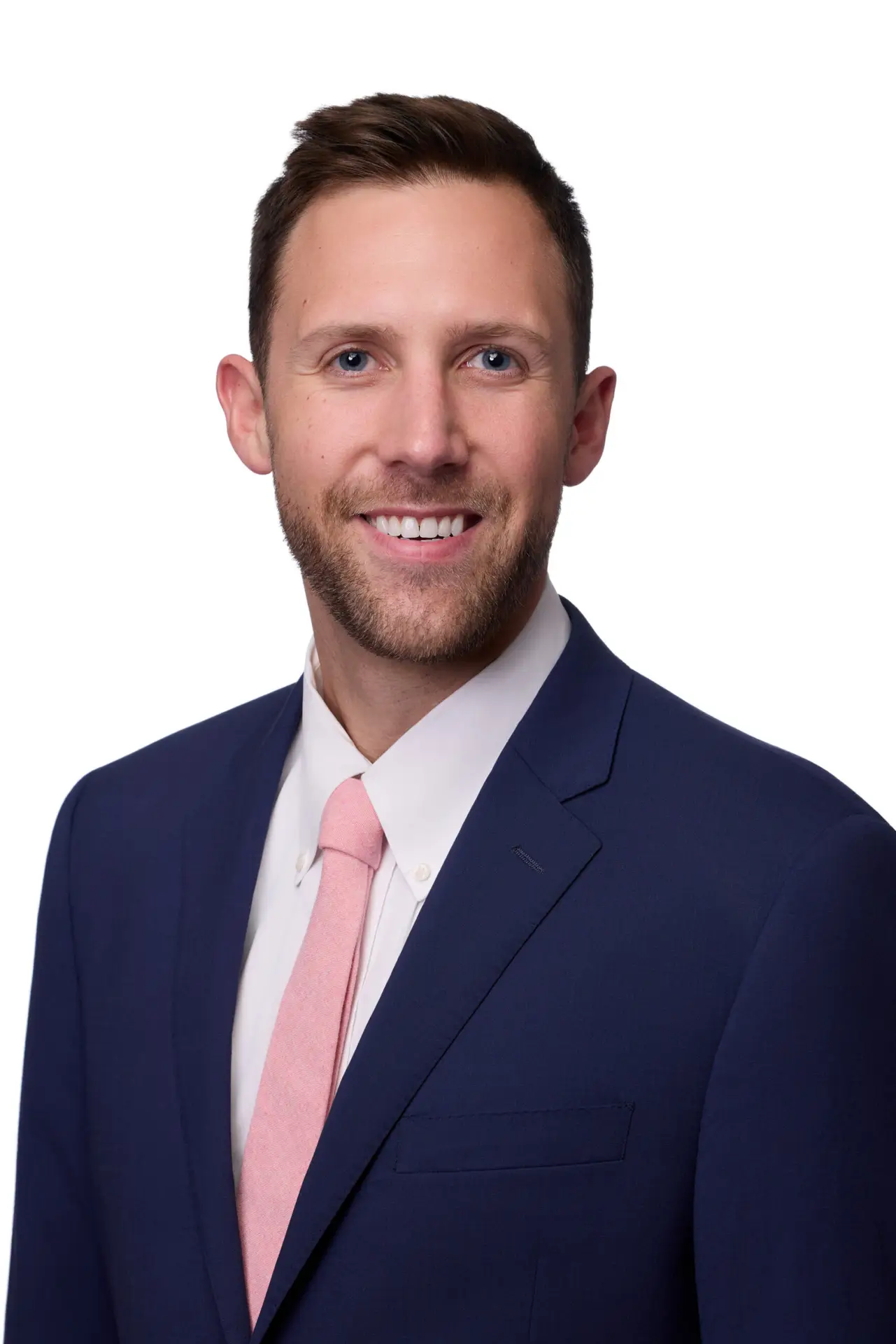 Business headshot of a man in a navy suit and pink tie on a white background