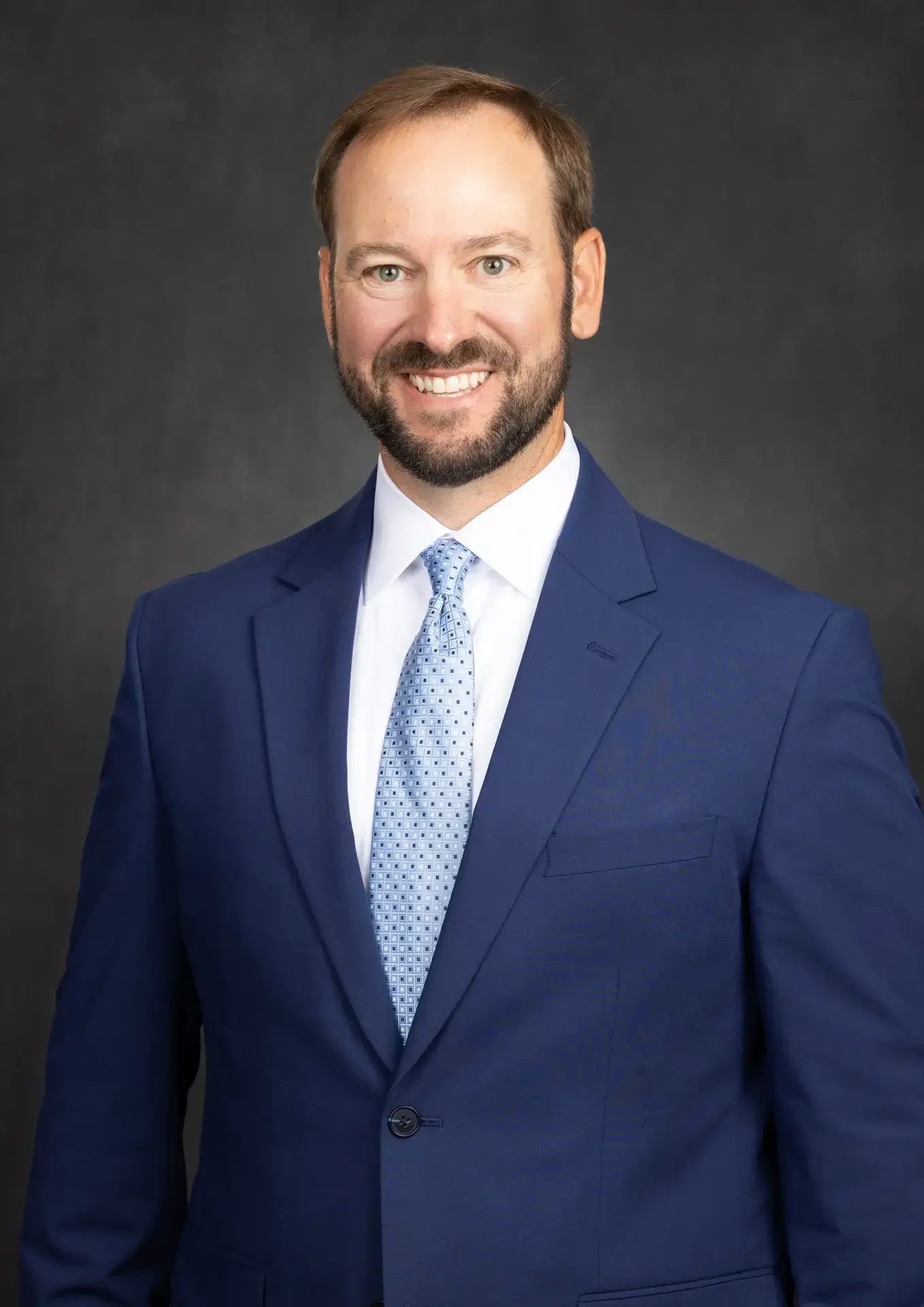 Corporate headshot of a man in a navy suit on a grey studio backdrop in Mandeville, Louisiana